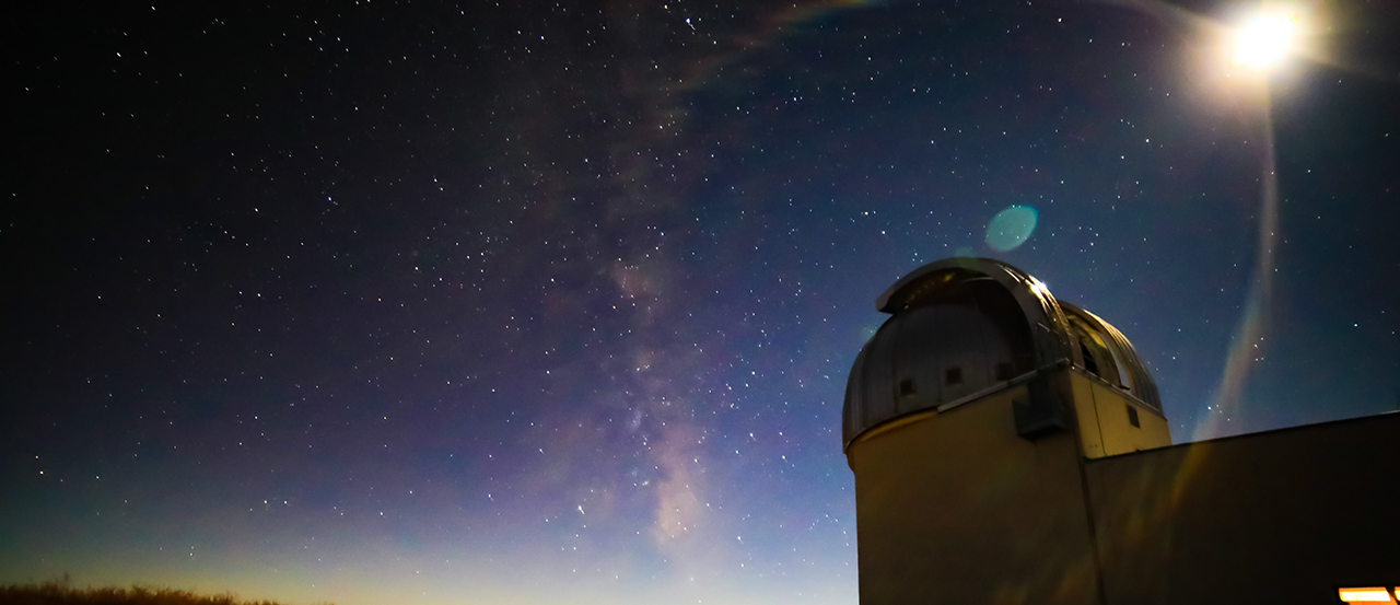 马格达莱纳岭天文台望远镜在日落时的图像. 外部视图是从地面看向望远镜，背景是星星.